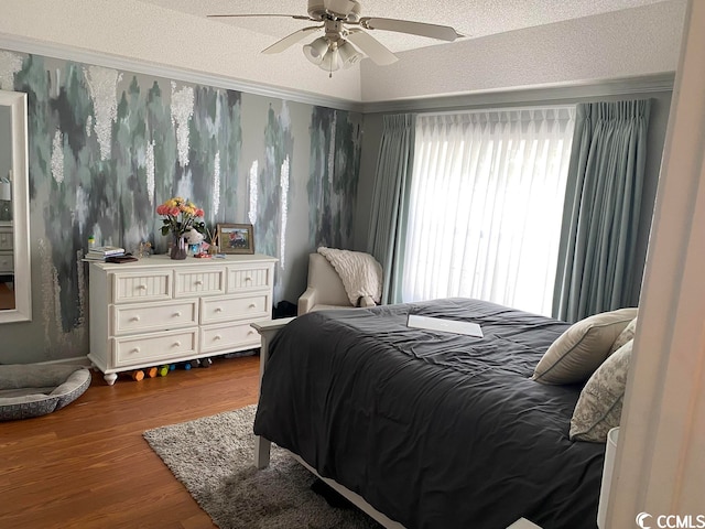 bedroom with hardwood / wood-style floors, a textured ceiling, multiple windows, and ceiling fan