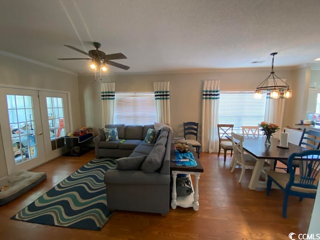 living room featuring hardwood / wood-style floors, a textured ceiling, ceiling fan with notable chandelier, crown molding, and french doors