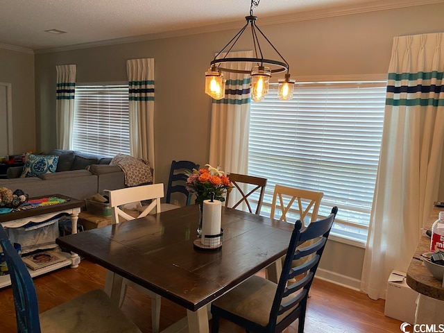 dining area featuring an inviting chandelier, a textured ceiling, crown molding, and hardwood / wood-style flooring