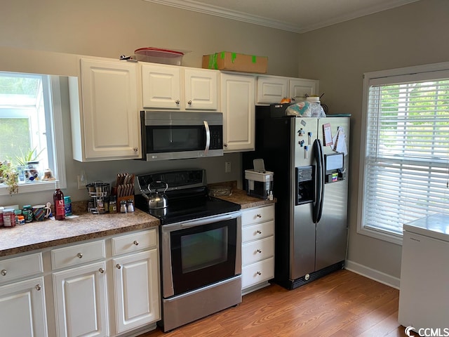 kitchen featuring stainless steel appliances, ornamental molding, white cabinetry, and light hardwood / wood-style floors