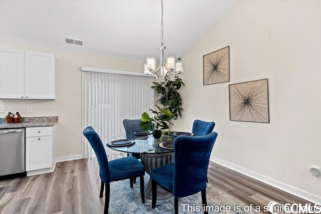 dining space featuring wood finished floors, visible vents, a chandelier, and baseboards