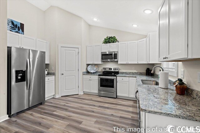 kitchen featuring light stone countertops, sink, light hardwood / wood-style floors, white cabinets, and appliances with stainless steel finishes