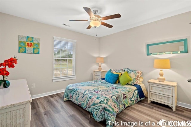 bedroom featuring visible vents, ceiling fan, baseboards, and wood finished floors