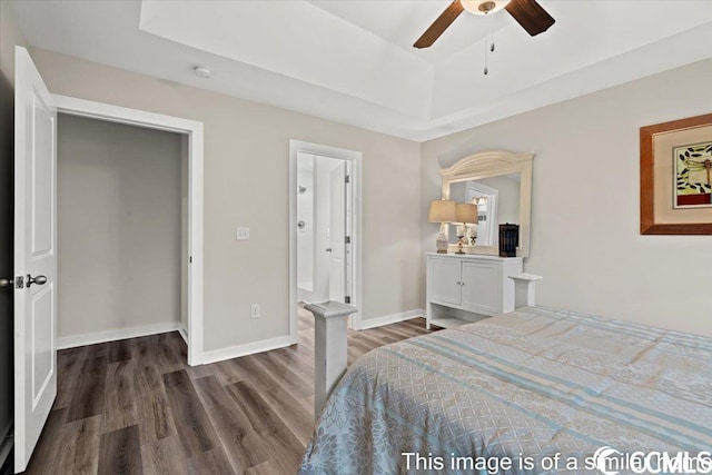 bedroom with baseboards, a tray ceiling, and wood finished floors