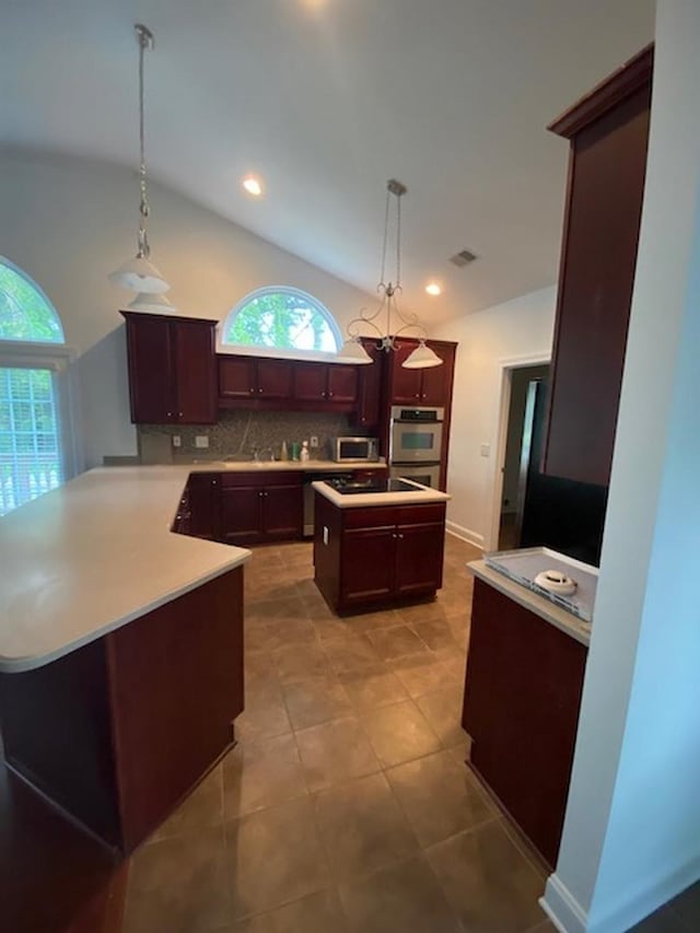 kitchen with vaulted ceiling, a kitchen island, pendant lighting, decorative backsplash, and stainless steel appliances