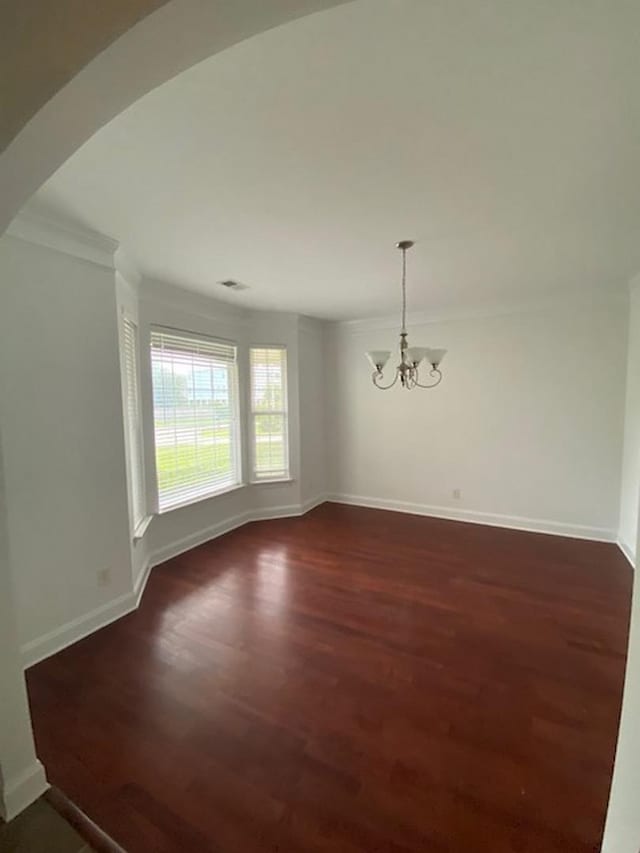 empty room featuring dark hardwood / wood-style flooring and a chandelier