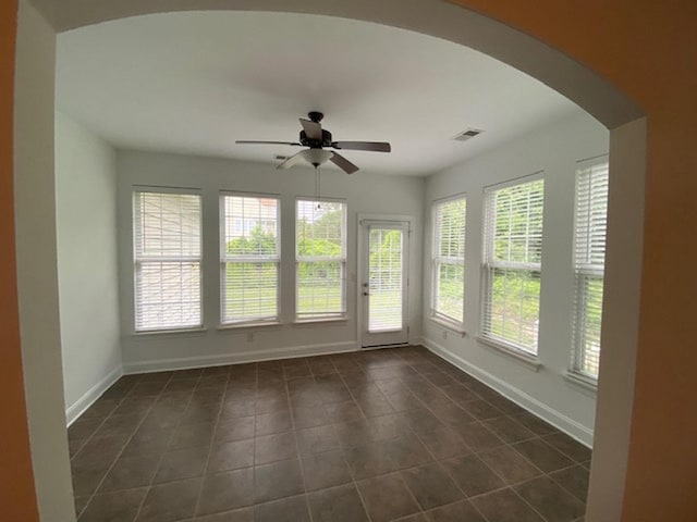 unfurnished sunroom featuring ceiling fan and a healthy amount of sunlight