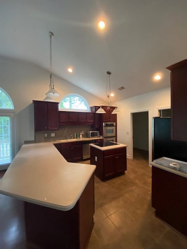 kitchen with appliances with stainless steel finishes, a center island, vaulted ceiling, and hanging light fixtures