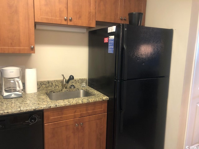 kitchen with light stone counters, black appliances, and sink