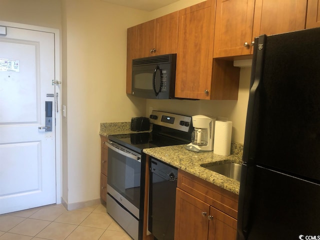 kitchen featuring sink, light stone counters, black appliances, and light tile flooring