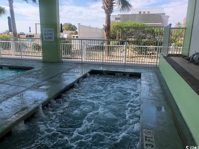 view of swimming pool featuring a hot tub