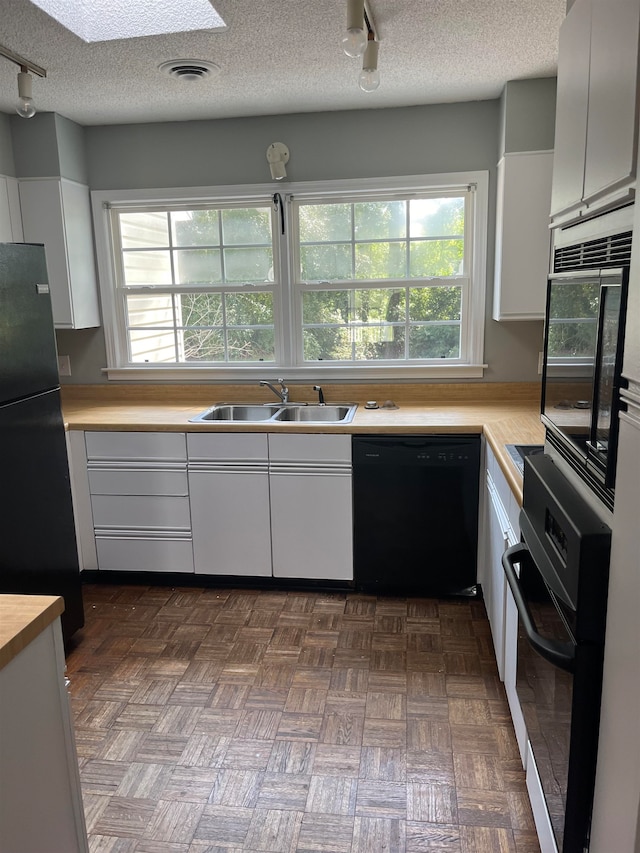 kitchen with a textured ceiling, dark parquet floors, black appliances, and sink