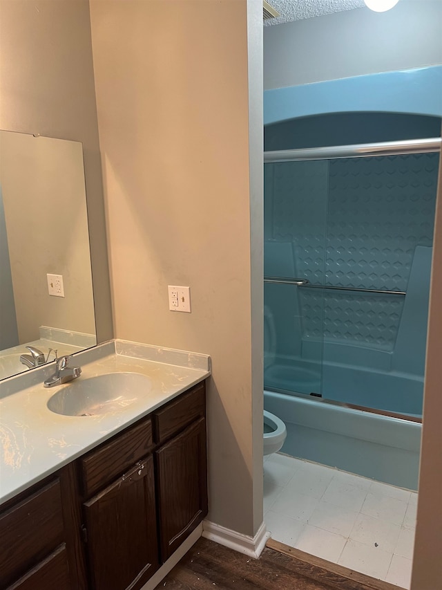 full bathroom with hardwood / wood-style flooring, bath / shower combo with glass door, toilet, and vanity