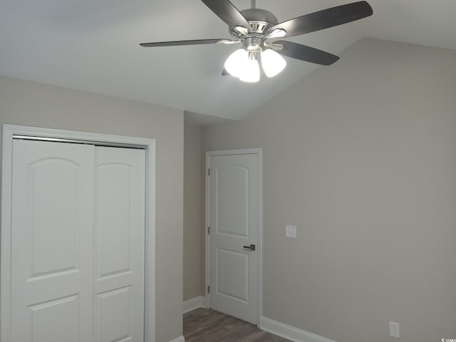 unfurnished bedroom with dark hardwood / wood-style flooring, a closet, vaulted ceiling, and ceiling fan