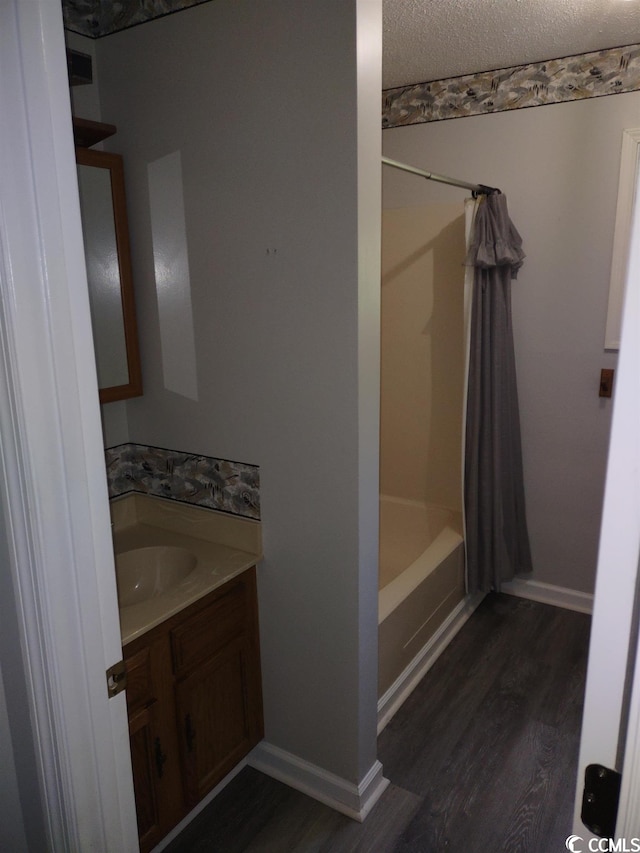 bathroom with shower / bath combo with shower curtain, a textured ceiling, hardwood / wood-style floors, and vanity