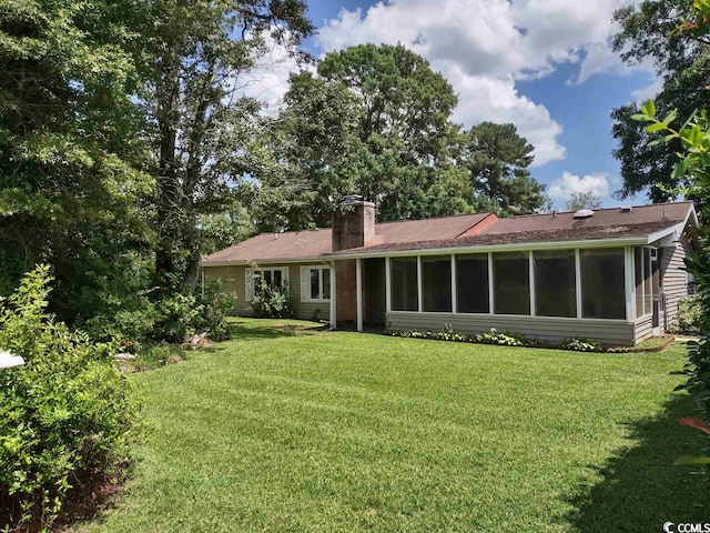 rear view of property featuring a sunroom and a yard