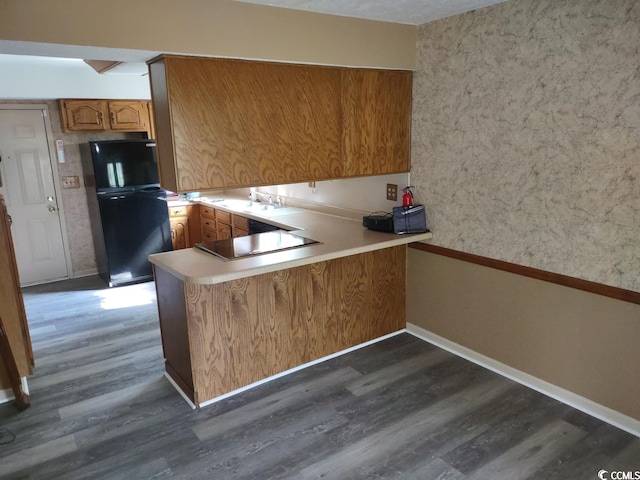 kitchen with kitchen peninsula, dark hardwood / wood-style flooring, and black appliances