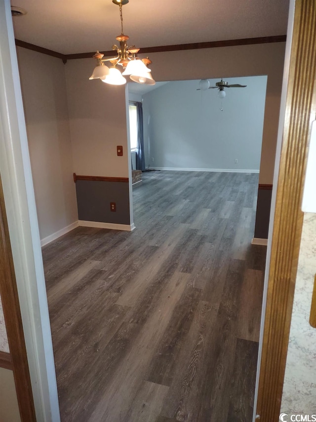 spare room featuring dark hardwood / wood-style floors, ornamental molding, and ceiling fan with notable chandelier