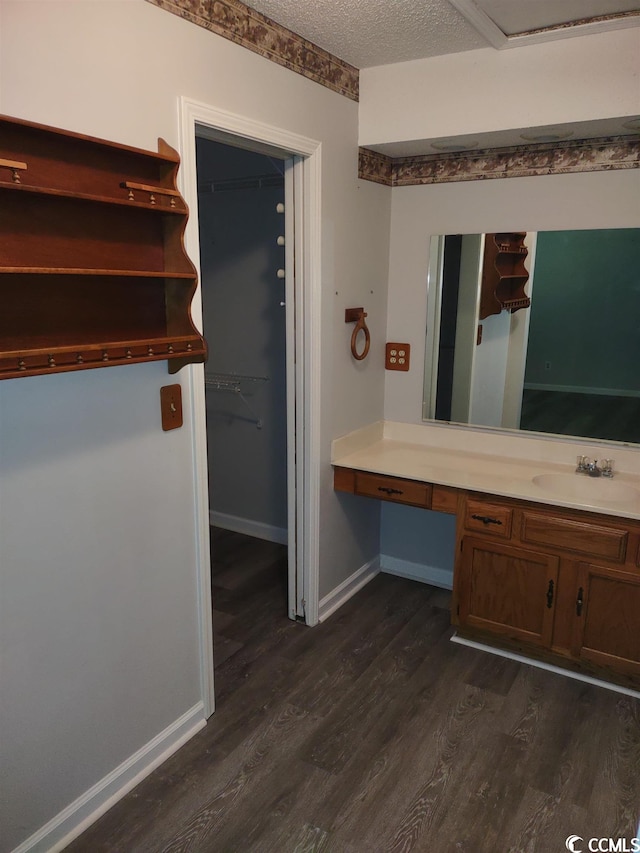 interior space with built in desk, a textured ceiling, dark hardwood / wood-style floors, and sink