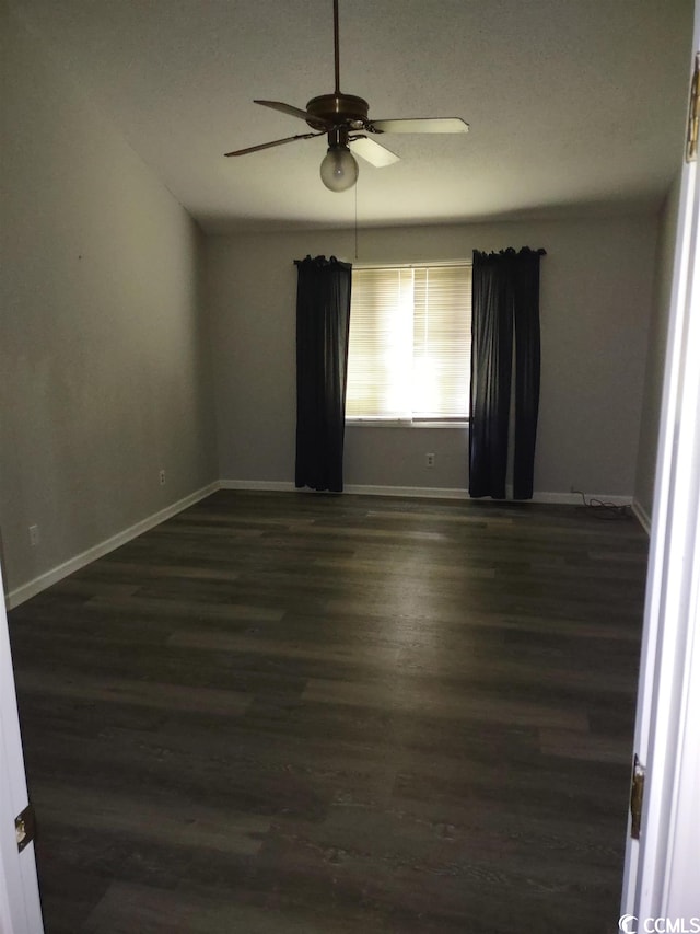 empty room with ceiling fan and dark wood-type flooring