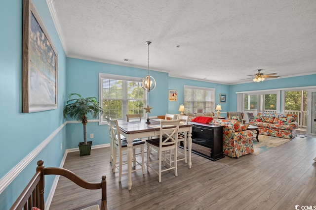 dining area featuring a textured ceiling, ceiling fan with notable chandelier, a wealth of natural light, and hardwood / wood-style flooring