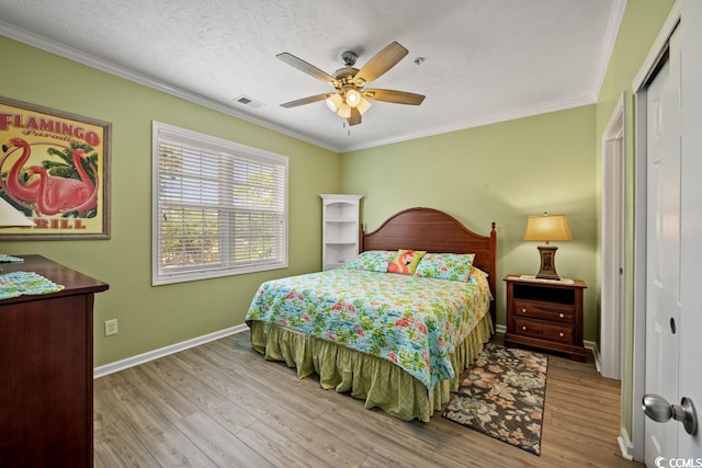 bedroom with ceiling fan, a textured ceiling, a closet, ornamental molding, and light hardwood / wood-style flooring