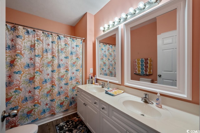 bathroom with double sink, oversized vanity, toilet, and hardwood / wood-style floors