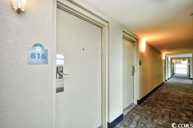 hall with dark colored carpet