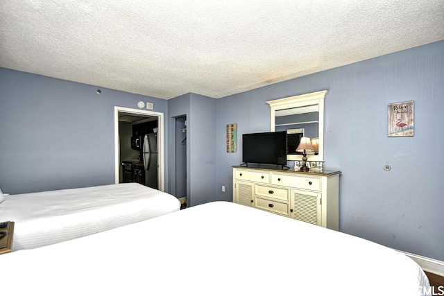 bedroom featuring a textured ceiling, stainless steel refrigerator, and a closet