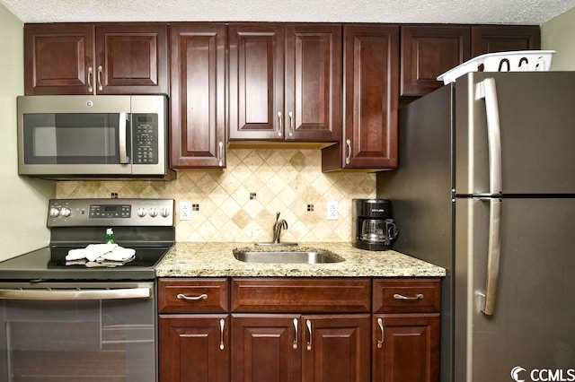 kitchen featuring light stone counters, sink, appliances with stainless steel finishes, and decorative backsplash