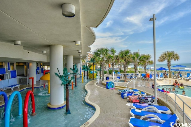 view of jungle gym featuring pool water feature, a community pool, and a water view