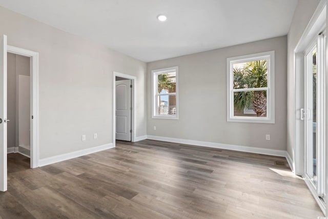 unfurnished bedroom featuring multiple windows and dark hardwood / wood-style flooring