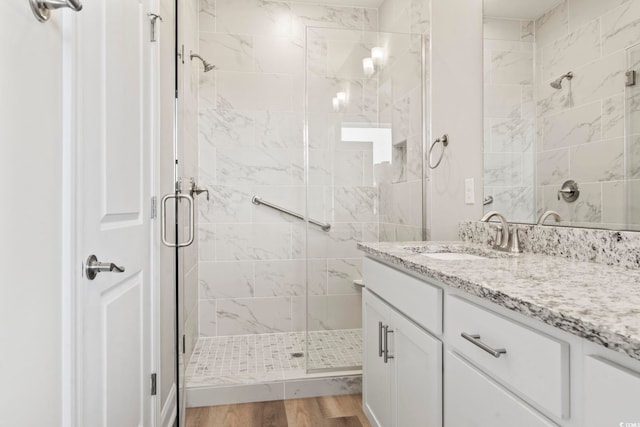 bathroom featuring hardwood / wood-style flooring, vanity, and walk in shower