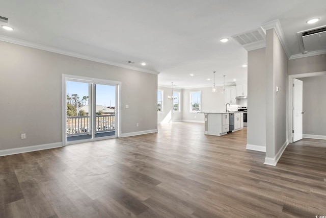 unfurnished living room with ornamental molding, sink, hardwood / wood-style floors, and an inviting chandelier