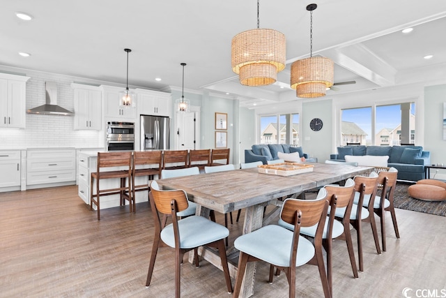 dining room with beamed ceiling, crown molding, and light hardwood / wood-style flooring