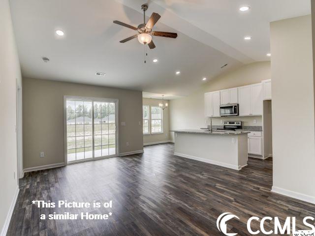 interior space featuring ceiling fan, vaulted ceiling, and dark wood-type flooring