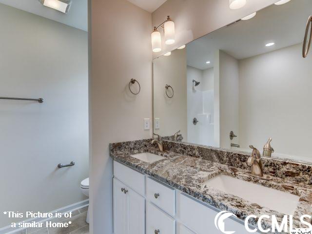 bathroom featuring double vanity, tile patterned floors, and toilet