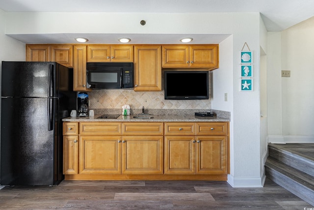 kitchen featuring light stone counters, dark hardwood / wood-style flooring, decorative backsplash, and black appliances