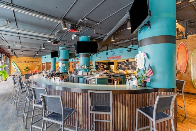 bar featuring hardwood / wood-style floors and track lighting