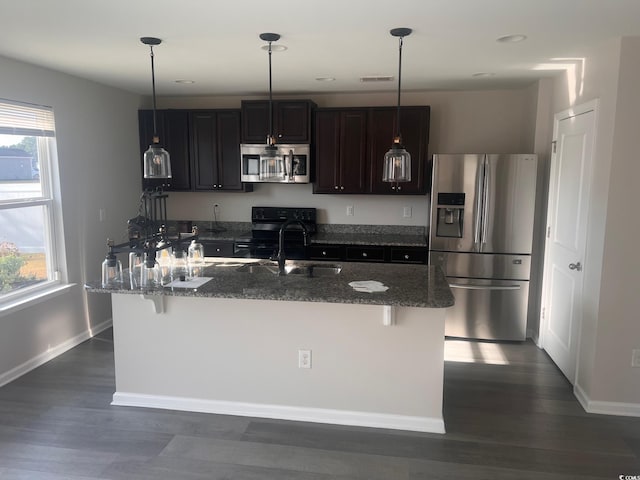 kitchen with a kitchen island with sink, sink, a breakfast bar, and appliances with stainless steel finishes