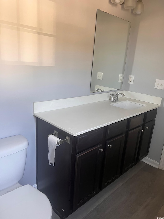 bathroom featuring wood-type flooring, toilet, and vanity