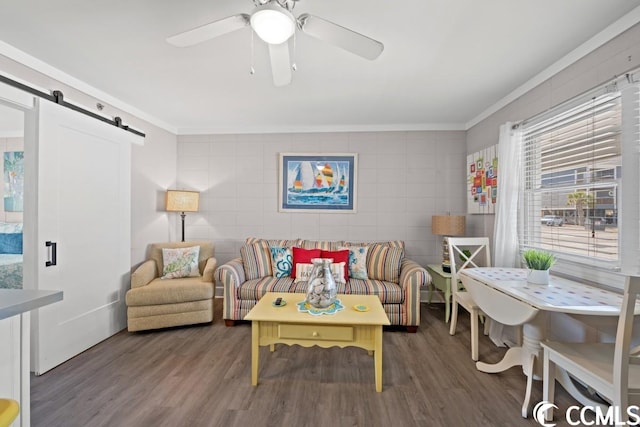 living room with ceiling fan, dark wood-type flooring, tile walls, a barn door, and crown molding