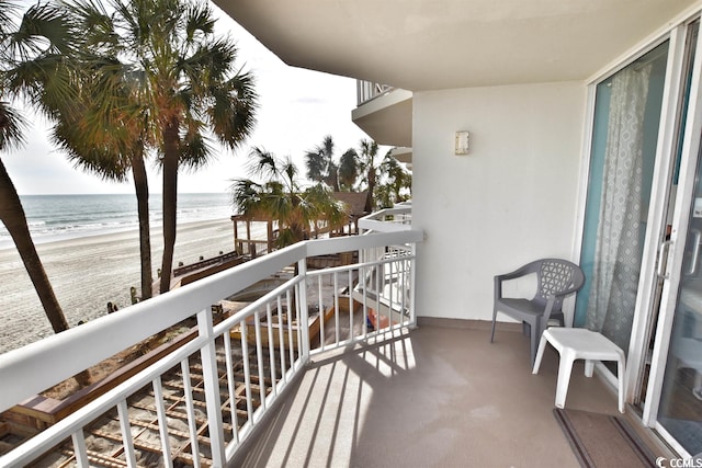 balcony with a water view and a view of the beach