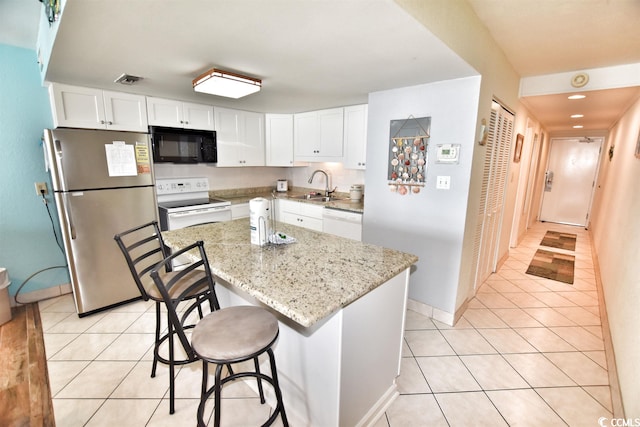 kitchen featuring light tile flooring, white appliances, white cabinets, light stone counters, and a kitchen island