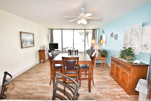 dining area with ceiling fan, a wall of windows, and light wood-type flooring