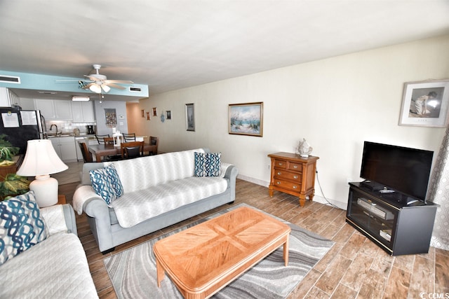 living room with sink, ceiling fan, and light hardwood / wood-style flooring