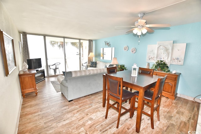 dining area featuring ceiling fan, light hardwood / wood-style flooring, and a wall of windows