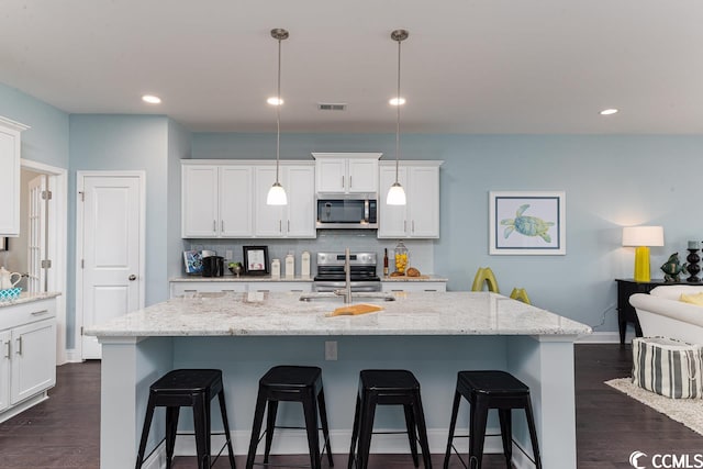 kitchen with a kitchen bar, appliances with stainless steel finishes, backsplash, and a sink