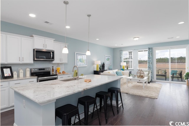 kitchen featuring a breakfast bar, a sink, white cabinets, appliances with stainless steel finishes, and dark wood finished floors