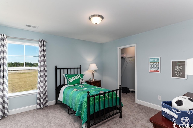 bedroom featuring carpet floors, baseboards, a spacious closet, and visible vents